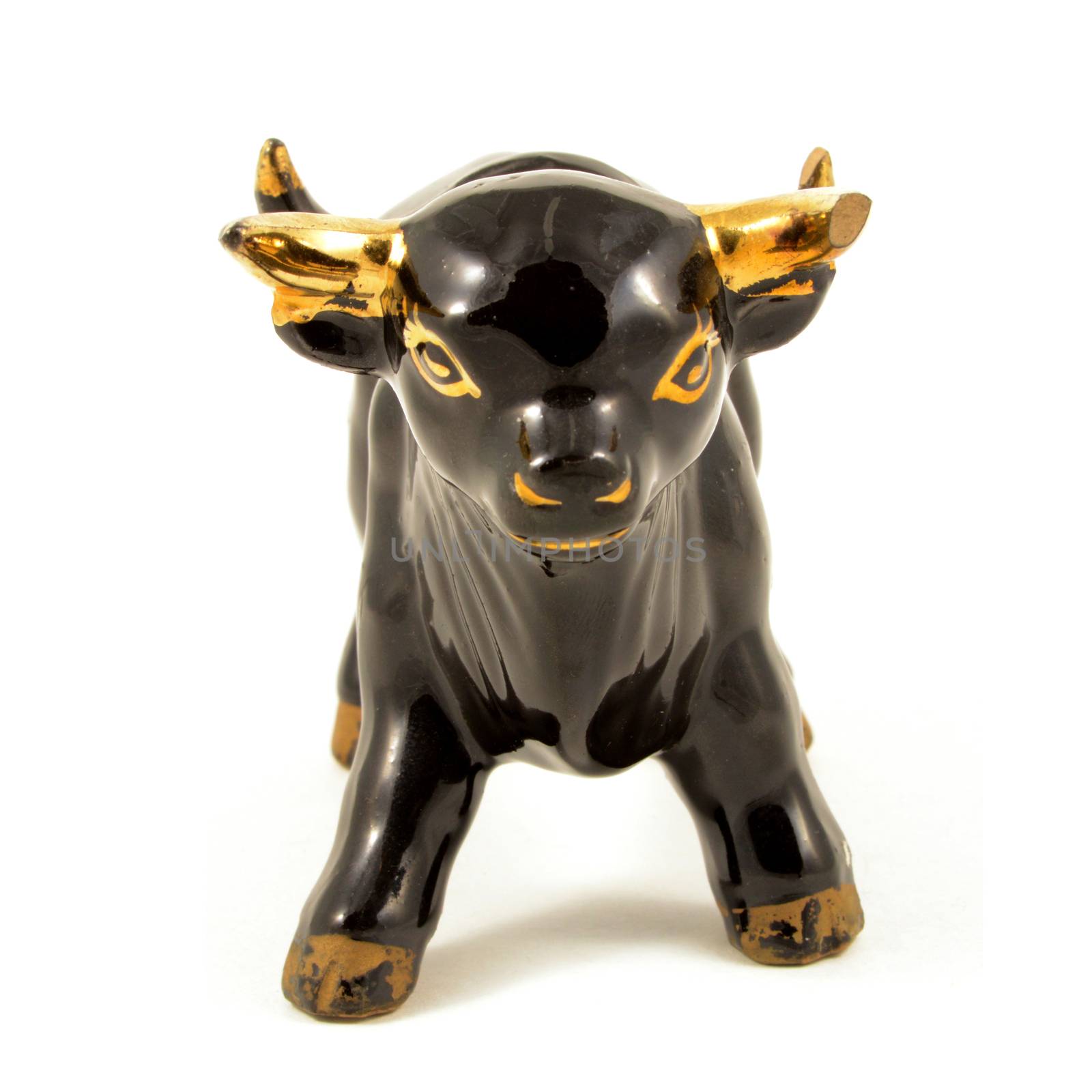 An isolated over a white background image of a frontal view porcelain black bull with gold highlights.