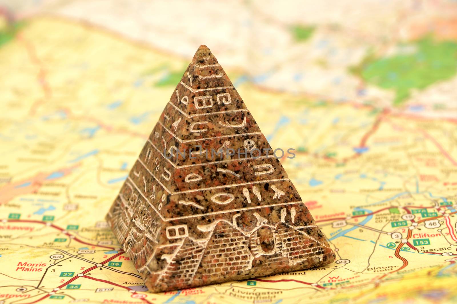 A small stone carved Egyptian Pyramid souvenir over top of a map for travel concepts.