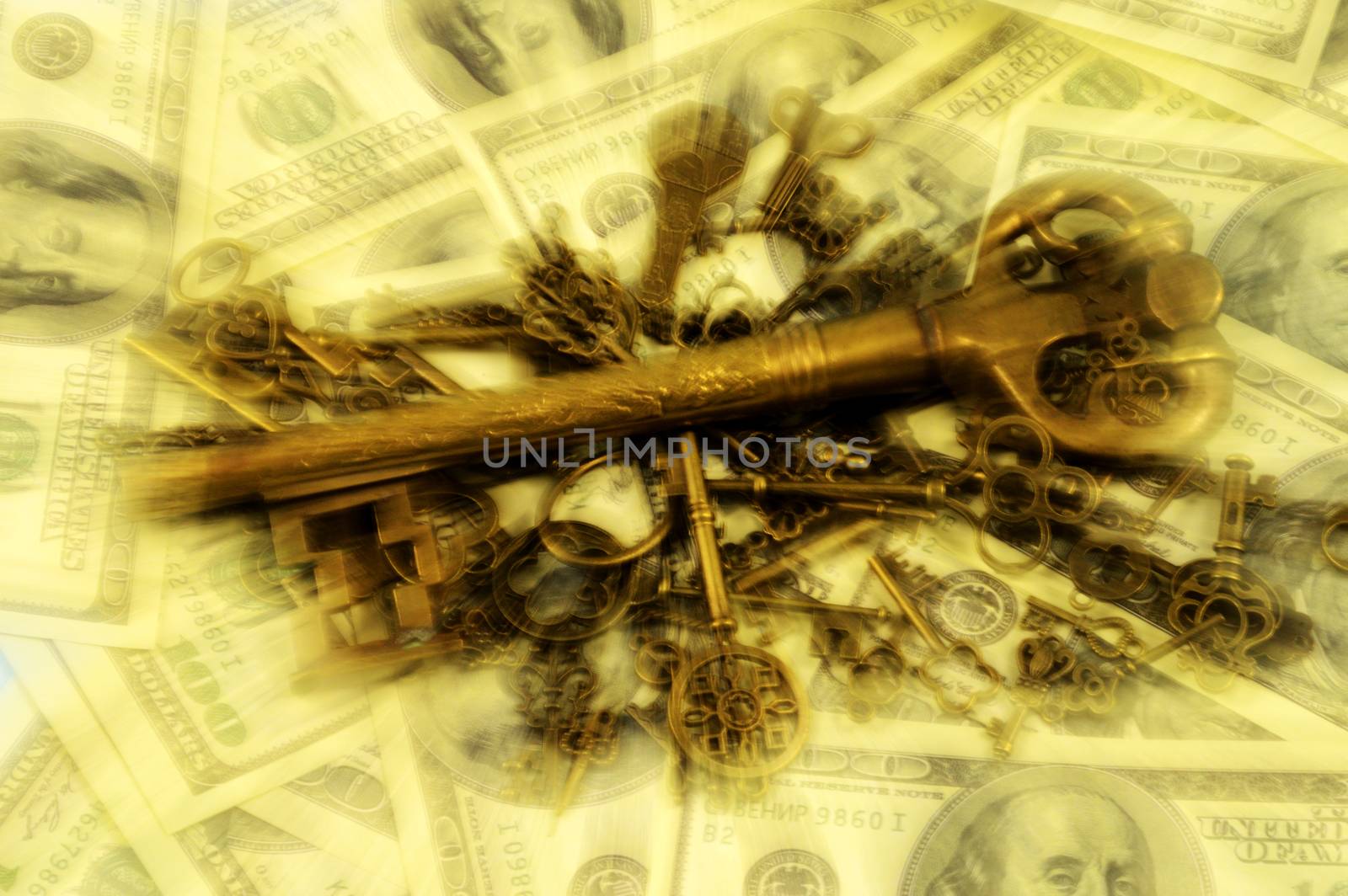 A lens blurred pile of brass keys with a larger dominant one centered on a background of American hundred dollar bills for creating a wealth strategy concept.