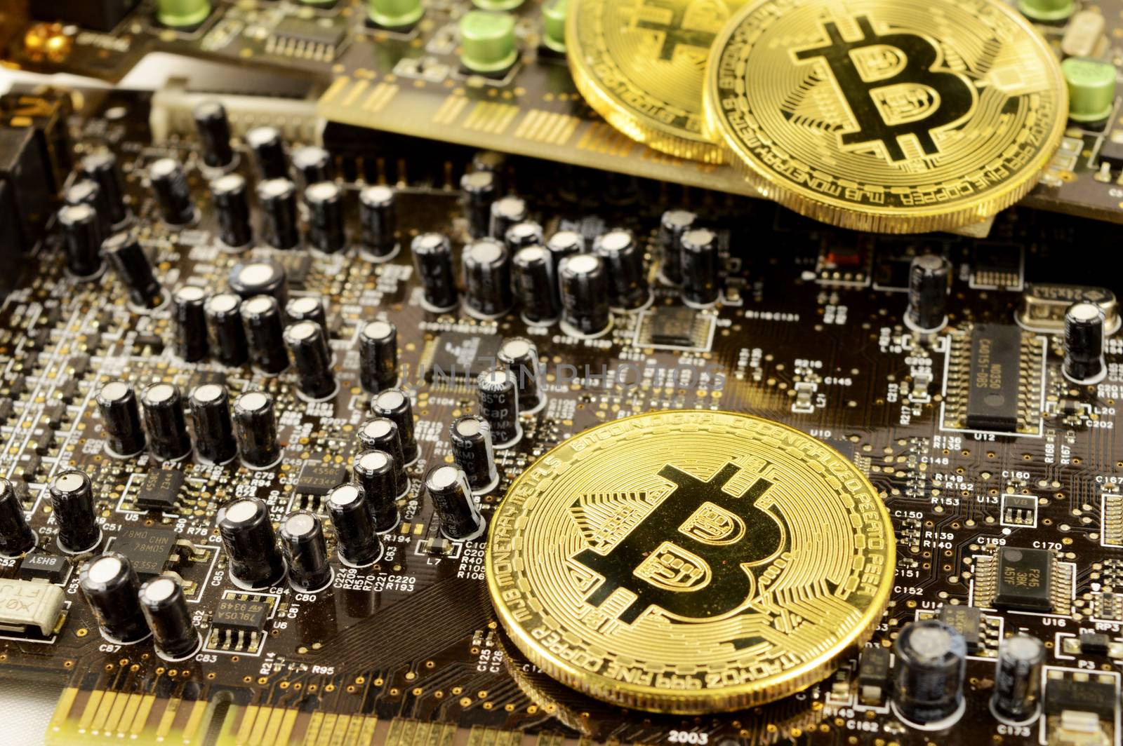 Closeup view of Bitcoins resting on top of a circuit board for showing the digital cryptocurrency details.