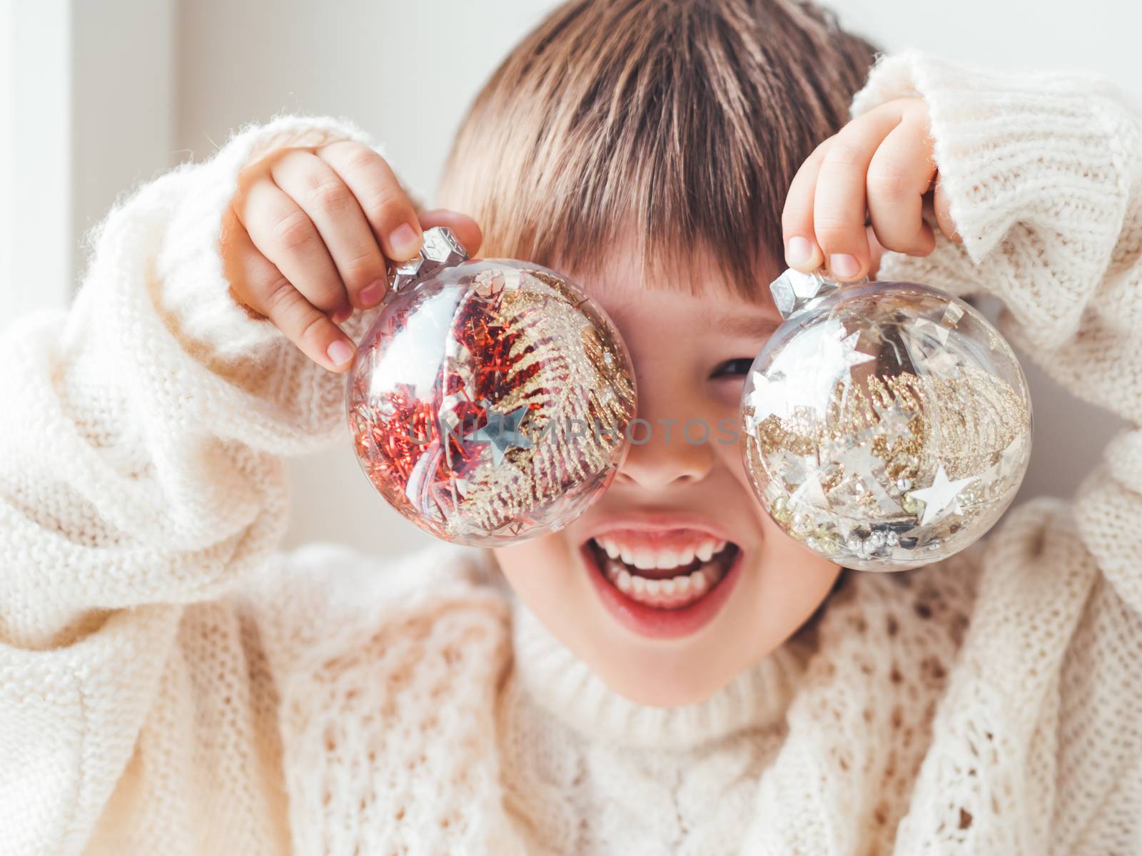 Kid with decorative balls for Christmas tree.Boy in cable-knit o by aksenovko