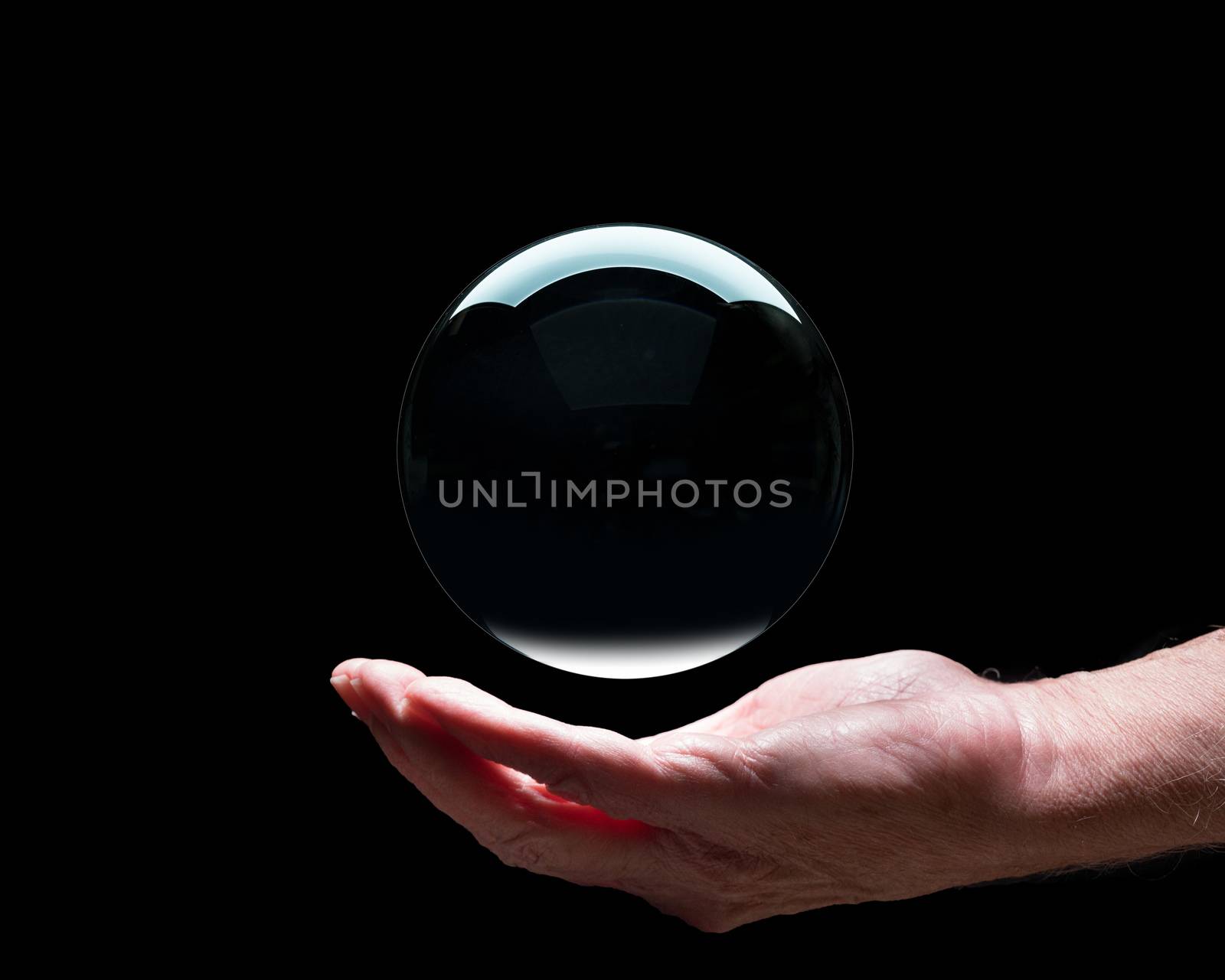 Senior caucasian hand holding a crystal futures or fortune telling ball with black center to suggest holding future in your palm