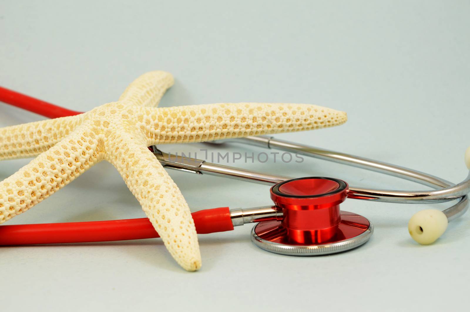 An illustrative tropical starfish and red medical stethoscope for concepts related to healthcare needed while on vacation.
