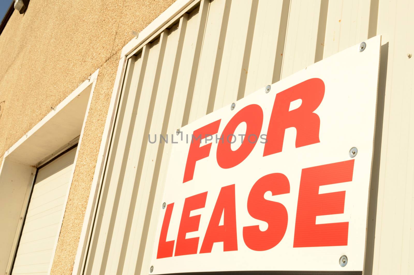 Closeup view of a large sign displaying the words for lease on the exterior of a commercial building.