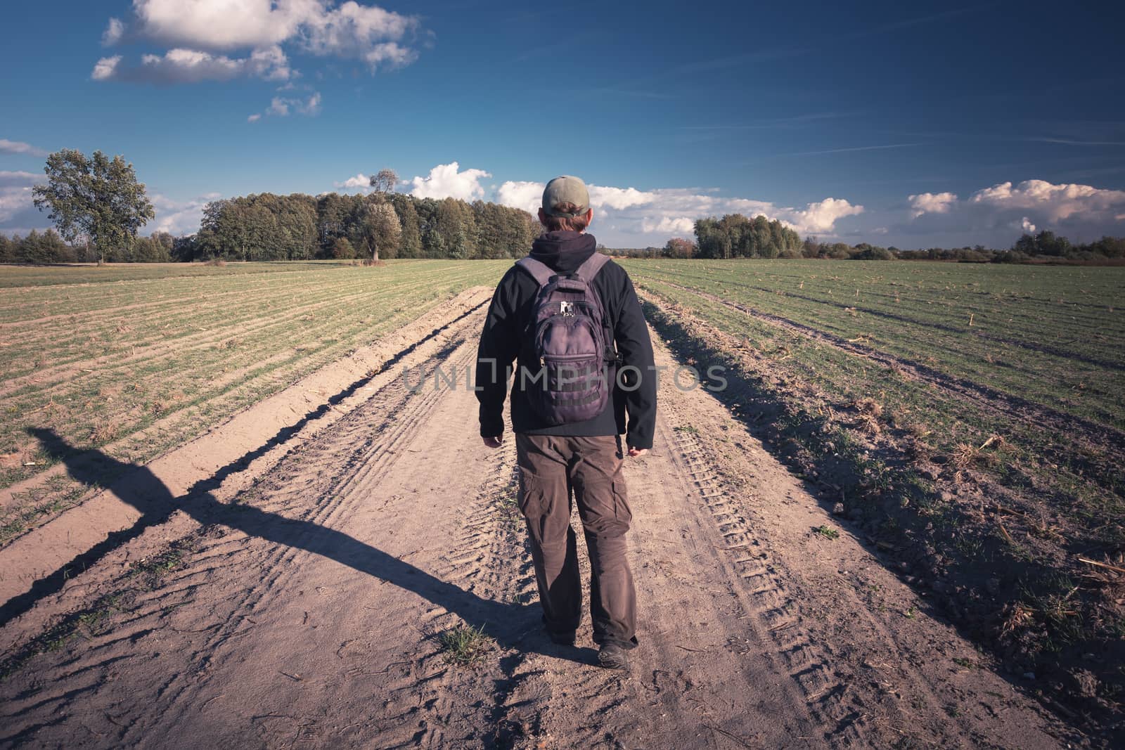 Traveler with backpack walking the dirt road by darekb22