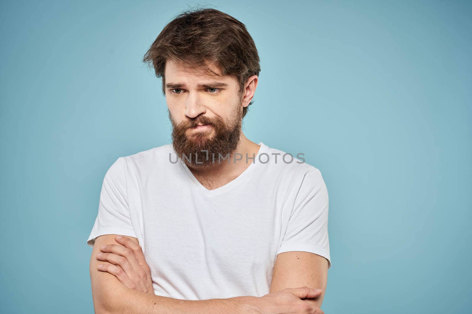 Man in white t-shirt lifestyle studio emotions facial expression blue isolated background by SHOTPRIME