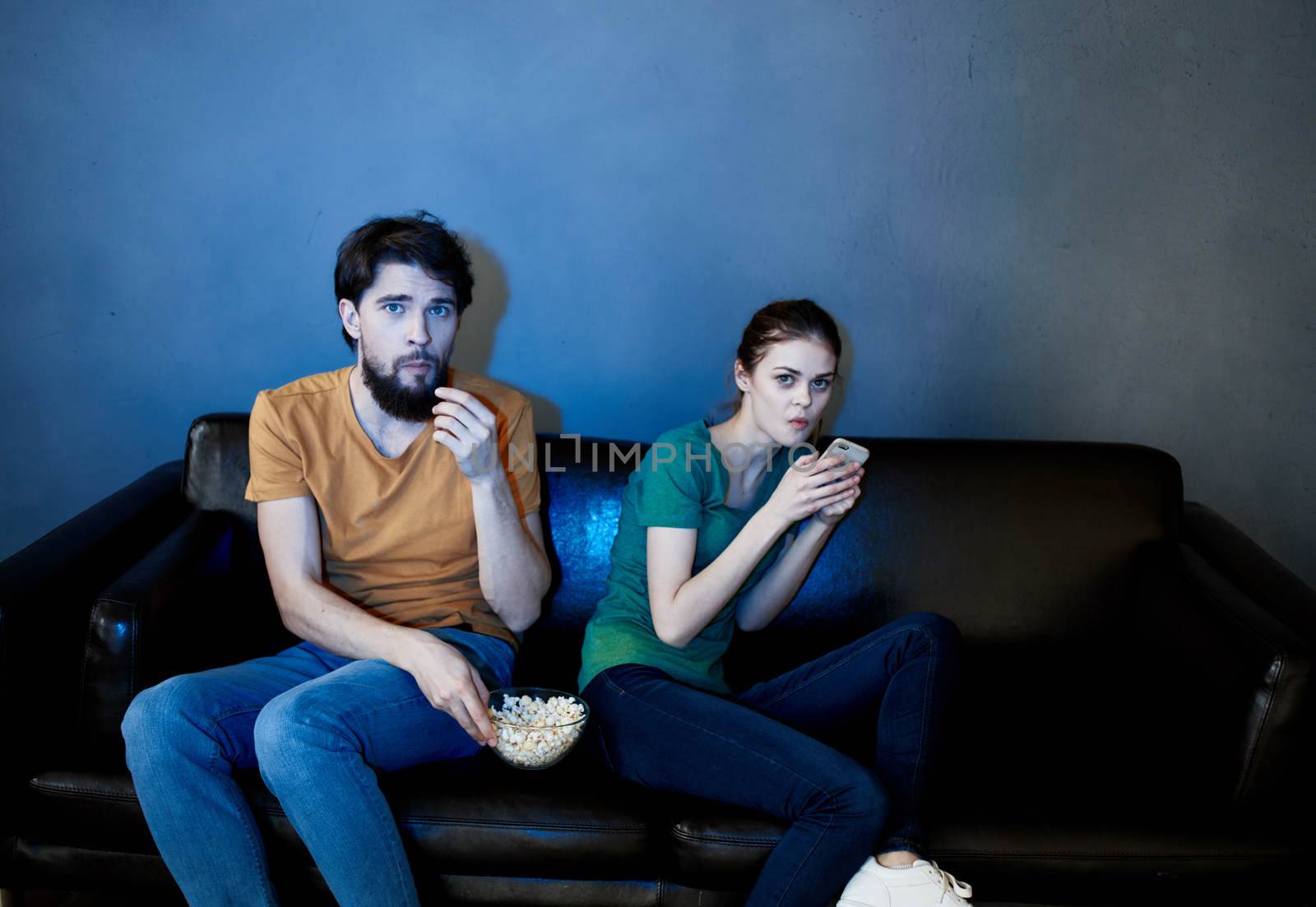A man and a woman are watching a movie in the cinema on the sofa indoors. High quality photo