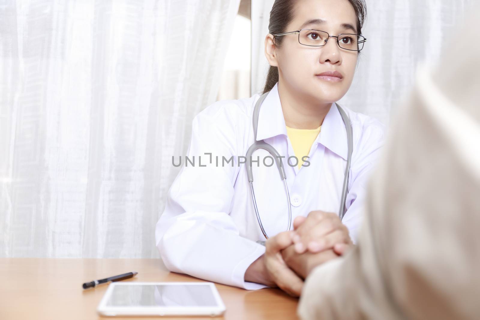 Doctor working in her clinic and listening to the patient, Doctor hold hand of patient and listening explaining his symptoms. healtcare and assistance concept
