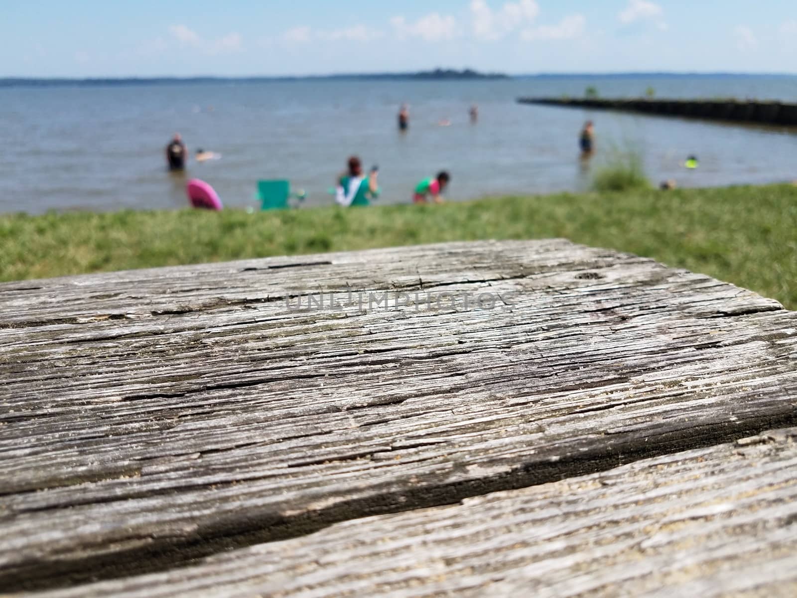 wood table and people in the water at a beach by stockphotofan1