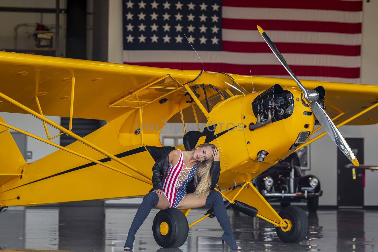 A beautiful blonde model poses with a vintage WWII aircraft