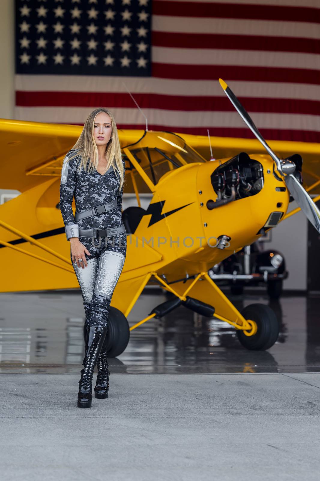 A beautiful blonde model poses with a vintage WWII aircraft