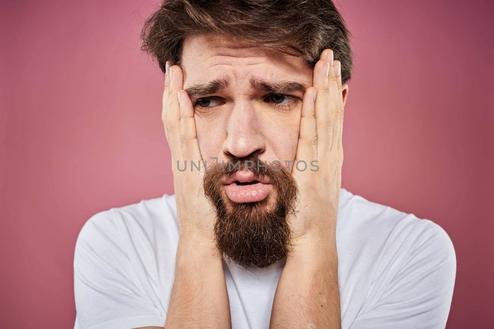 bearded man in white t-shirt emotions displeased facial expression studio pink background by SHOTPRIME