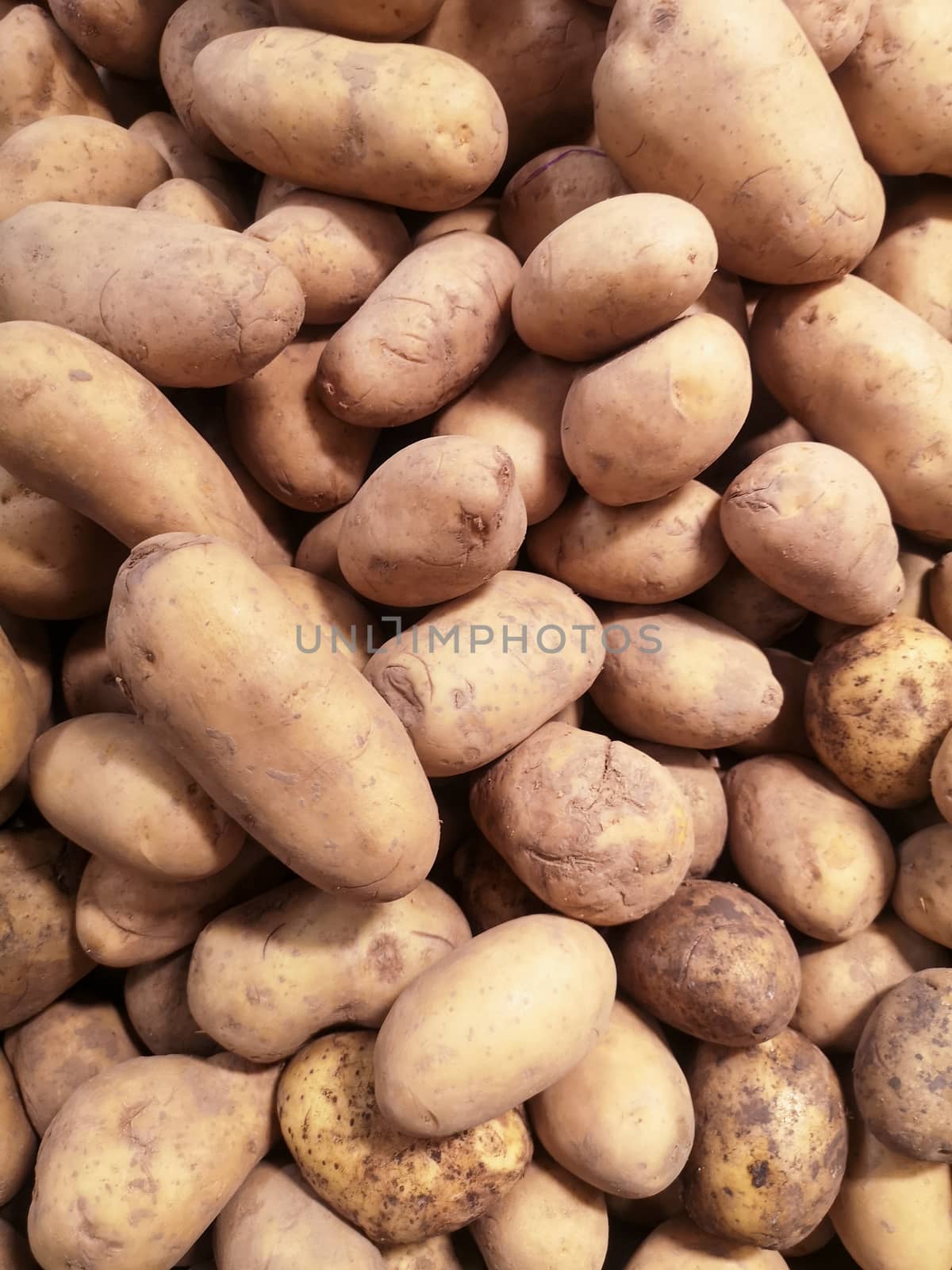 Unwashed potatoes in a supermarket on a store counter for sale.