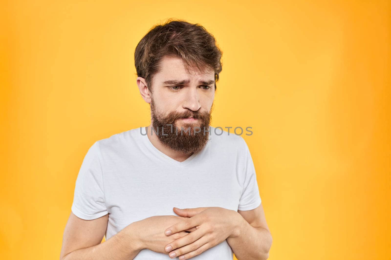 A man in a white t-shirt gestures with his hands studio lifestyle yellow background emotions by SHOTPRIME