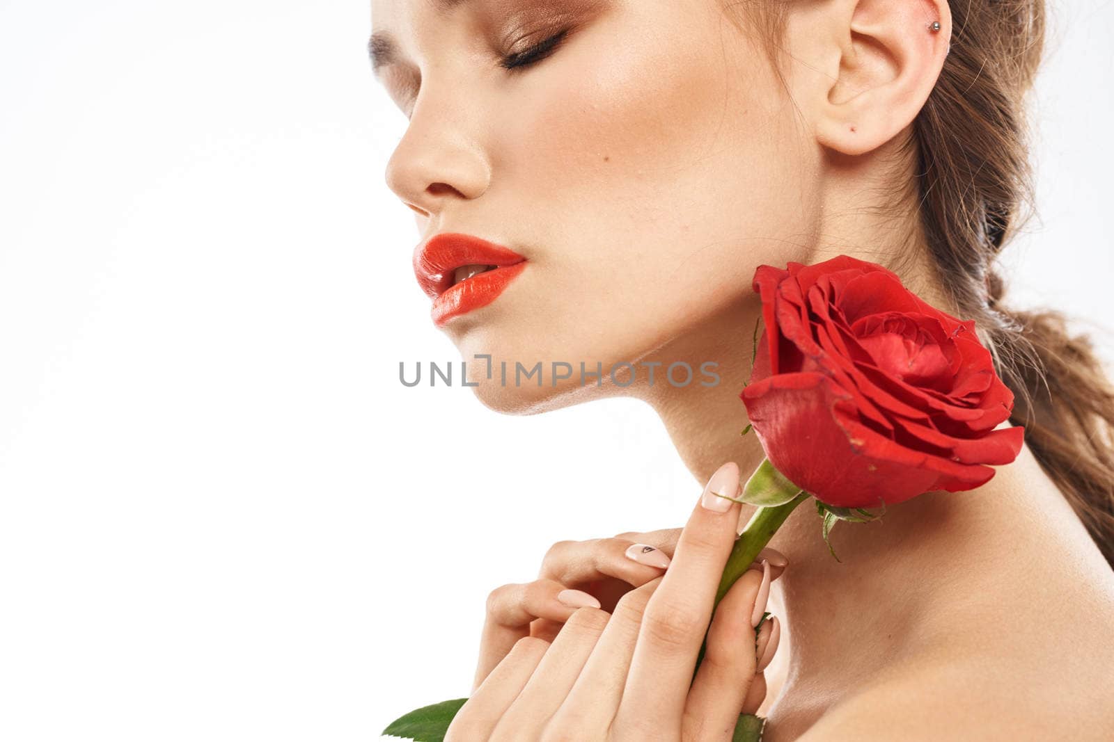 Beautiful woman with red rose near face makeup naked shoulders portrait. High quality photo
