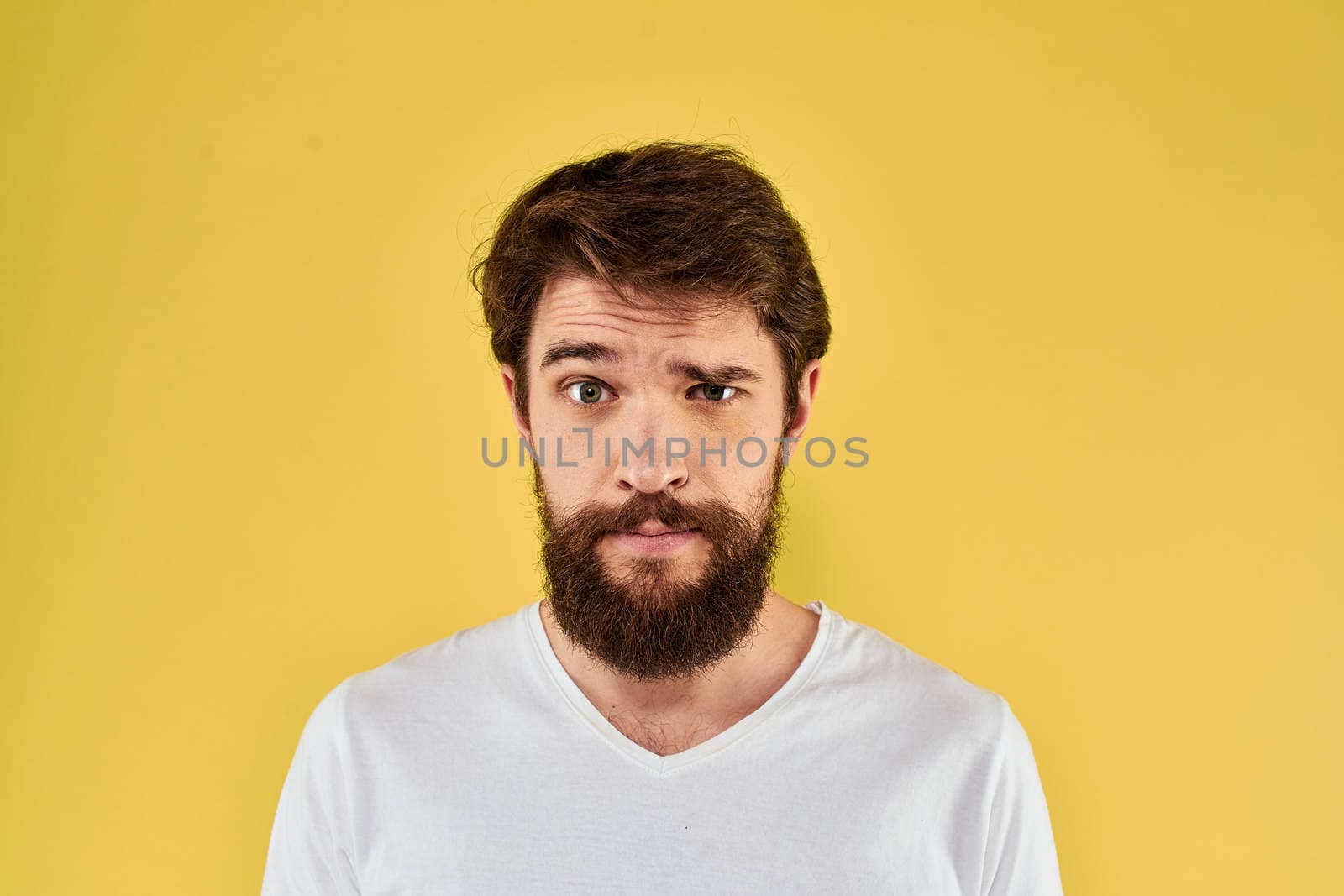 A man in a white t-shirt gestures with his hands lifestyle cropped view yellow background more fun. High quality photo