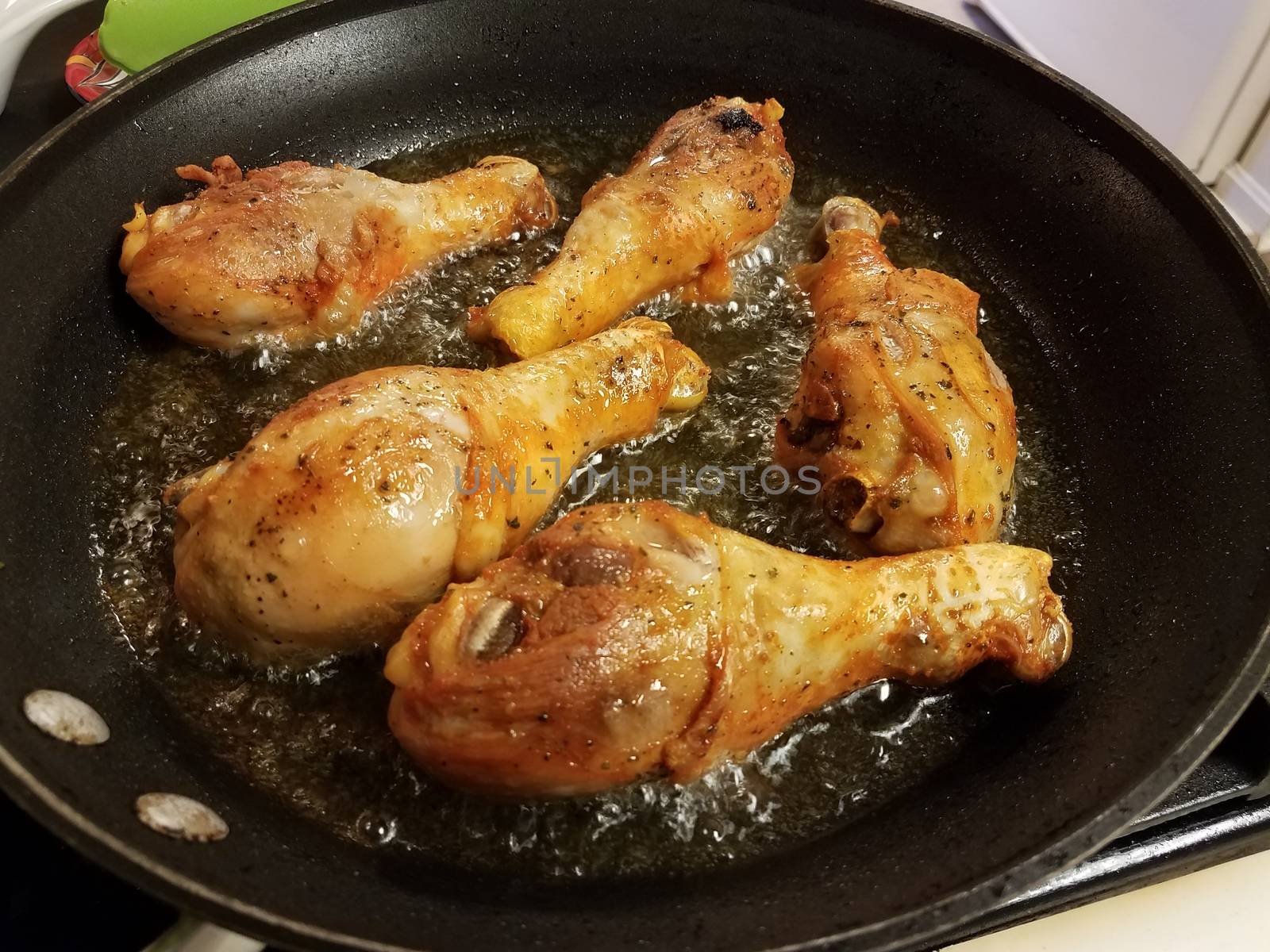 chicken drumsticks boiling in hot oil in frying pan