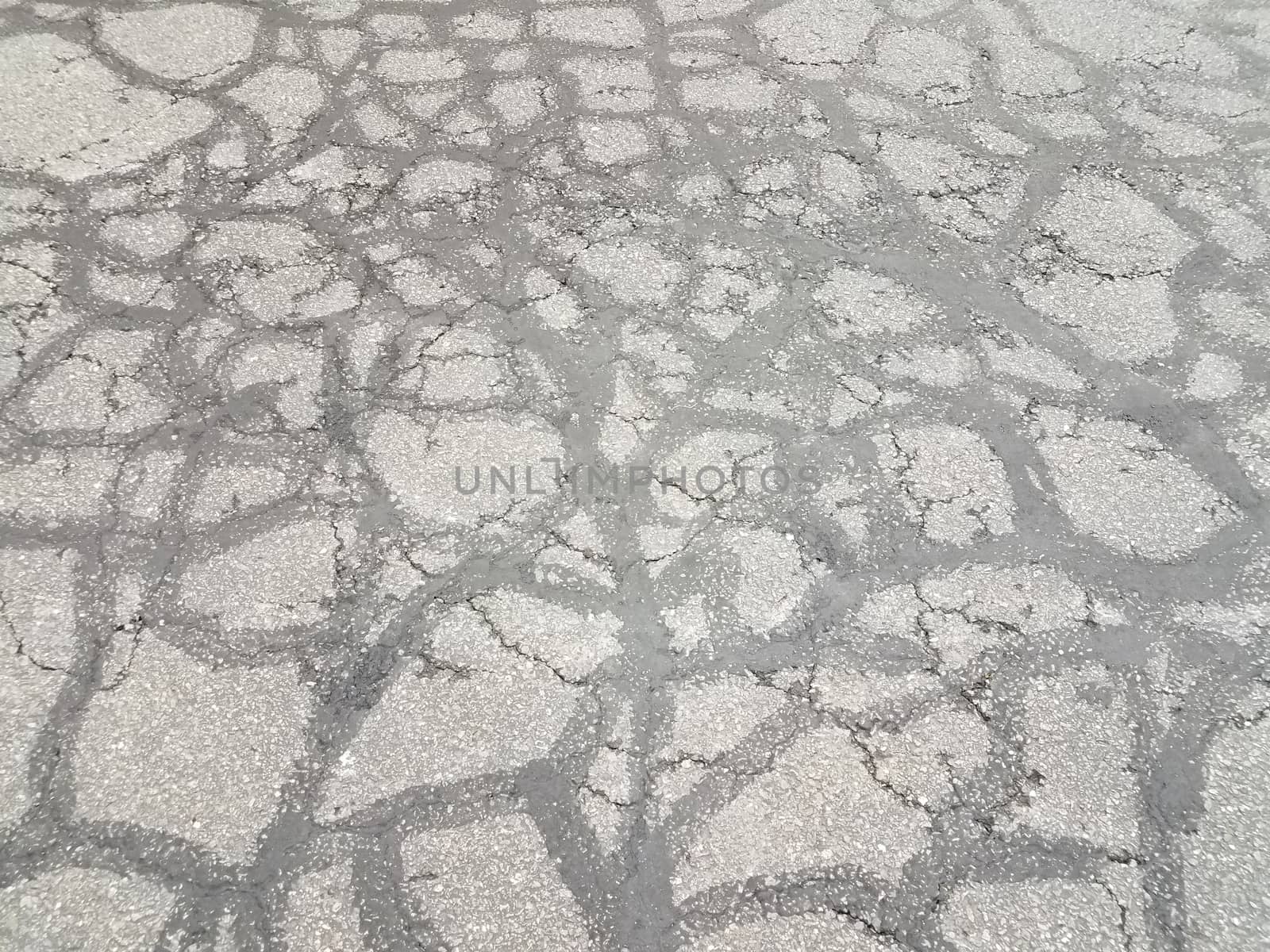 cracks and lines in damaged black asphalt or pavement by stockphotofan1