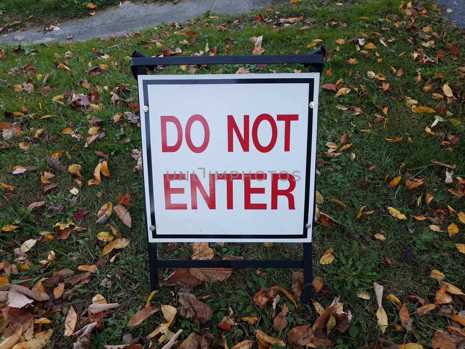 red and white do not enter sign on grass with leaves