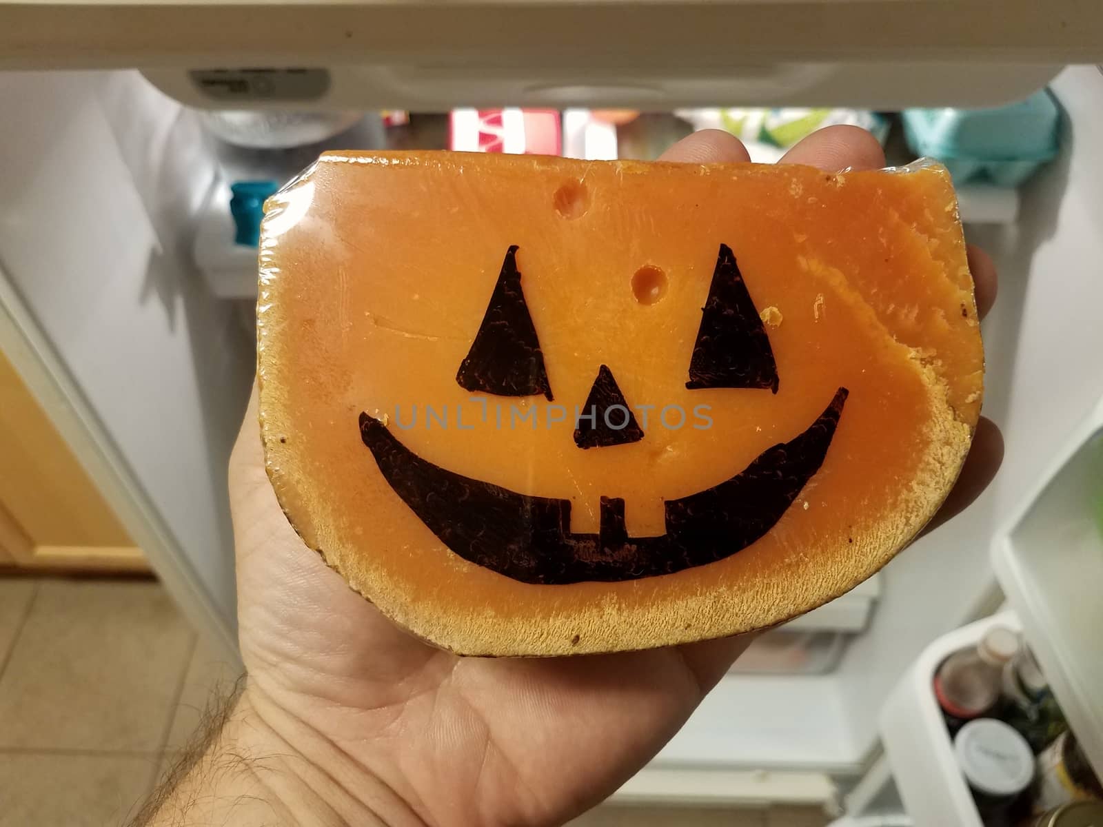 orange cheese with Halloween pumpkin face and hand in refrigerator