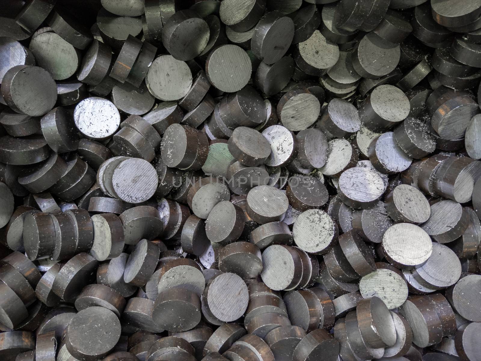 A pile of sawed cylindrical steel workpieces. Full frame close-up abstract industrial background.