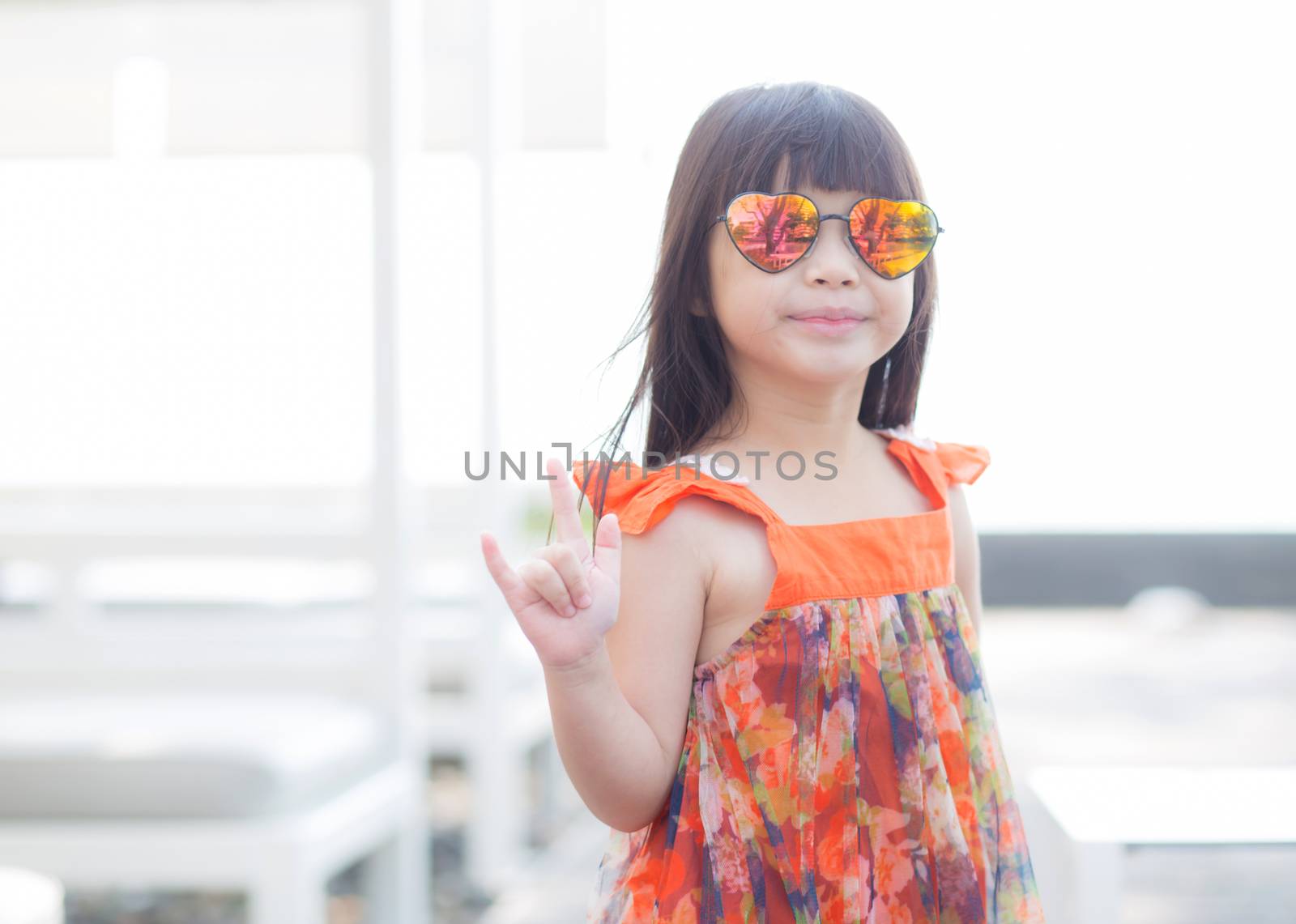 Beautiful portrait little girl asian of a smiling standing at swimming pool, kid leisure and joyful wear glasses in outdoor.