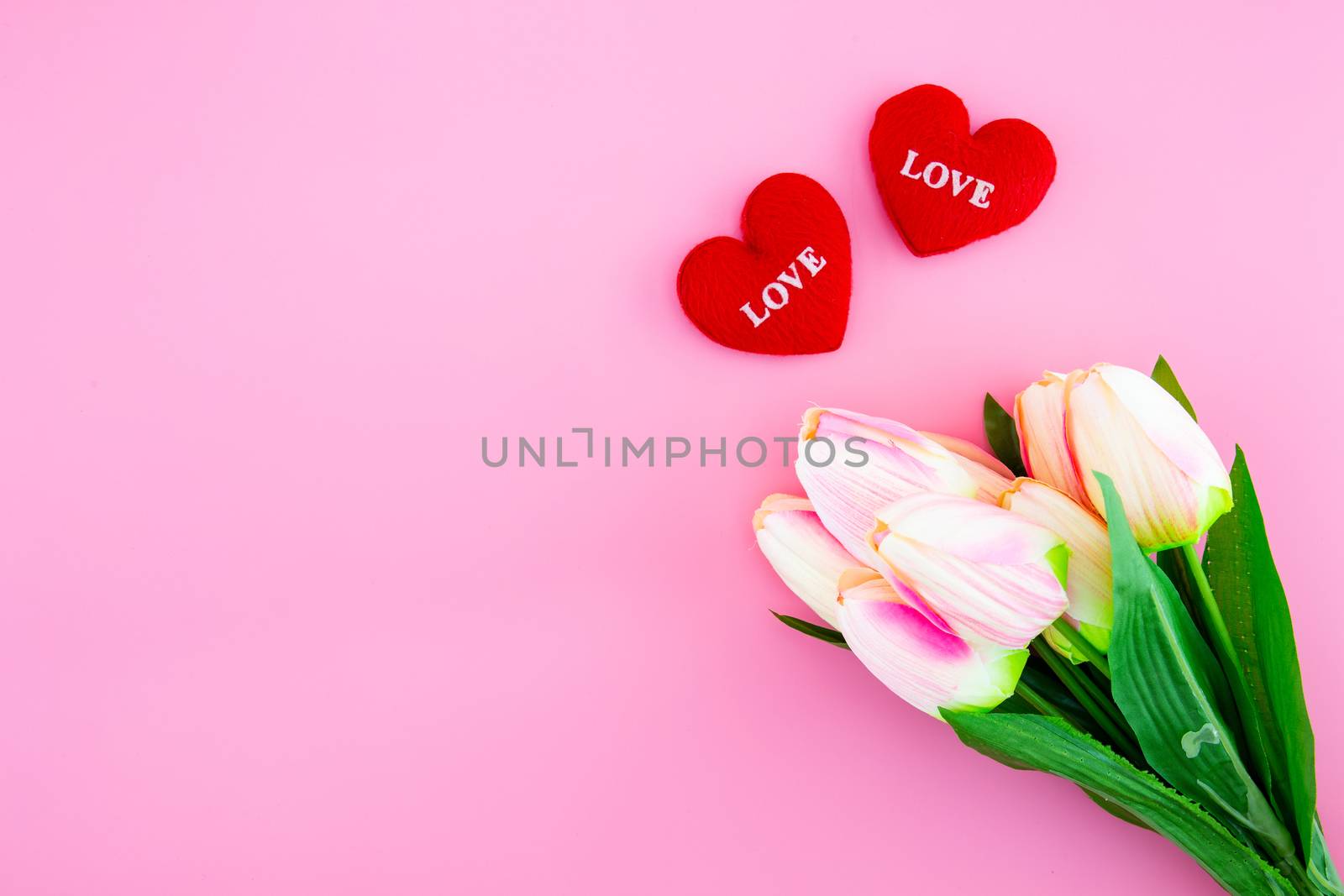 Beautiful of yellow tulip flower and heart shape pillow with flat lay on the pink background, top view, mother day and holiday concept, copy space.