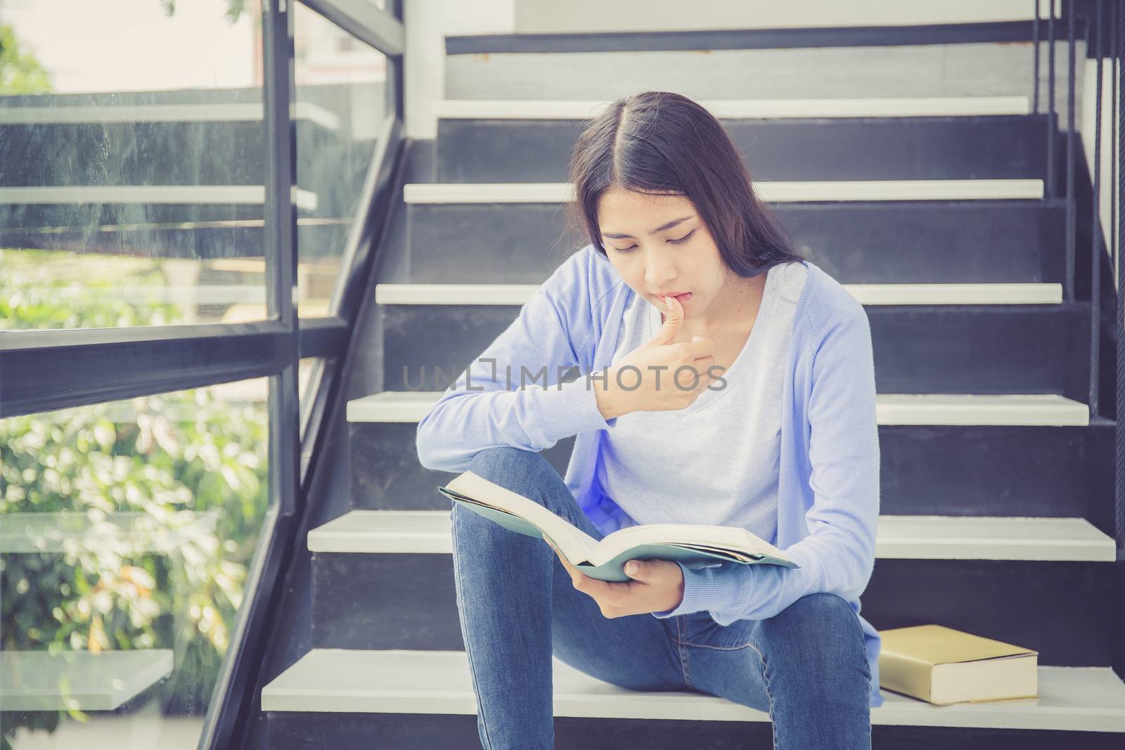 Beautiful of portrait asian young woman holding book, girl tired and bored reading book studying for exams, education and lifestyle concept.