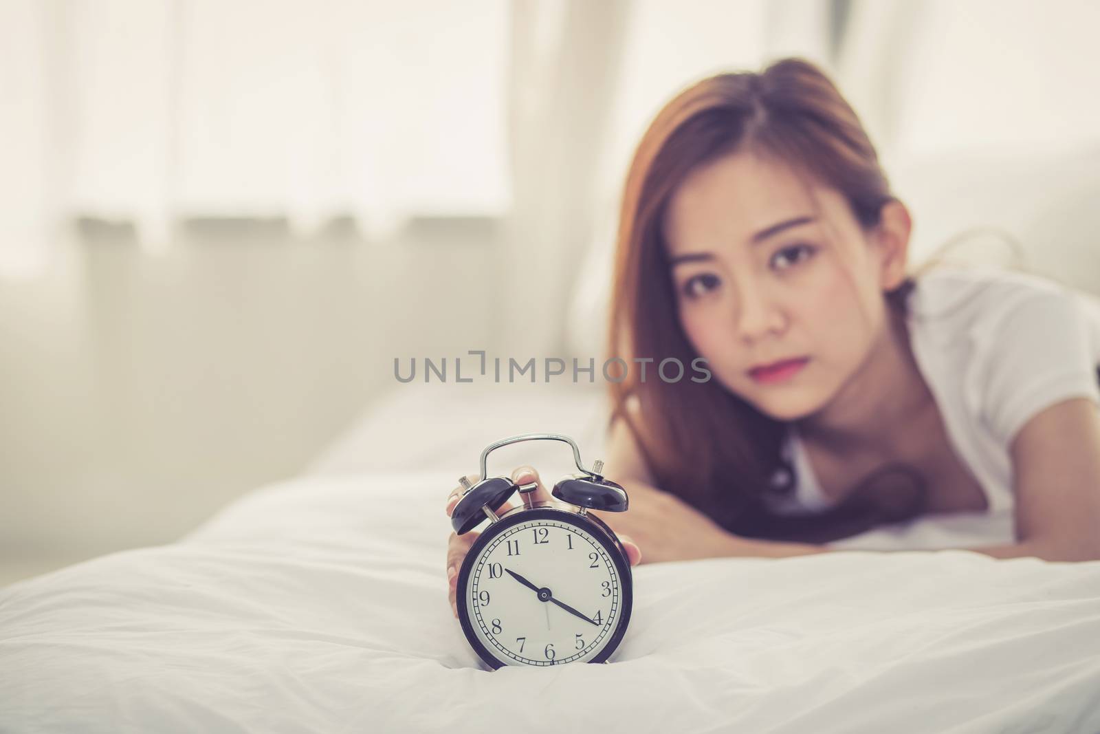 Beautiful asian young woman turn off alarm clock in good morning, wake up for sleep with closeup foreground alarm clock, relax and lifestyle concept.