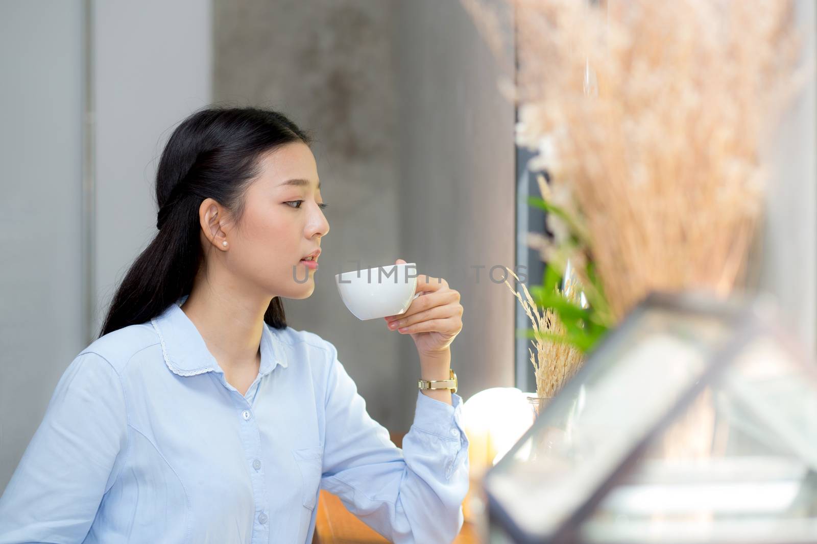 Beautiful  young asian woman drinking coffee and smile in the morning at cafe, girl sitting in coffee shop for breakfast and leisure during free time.