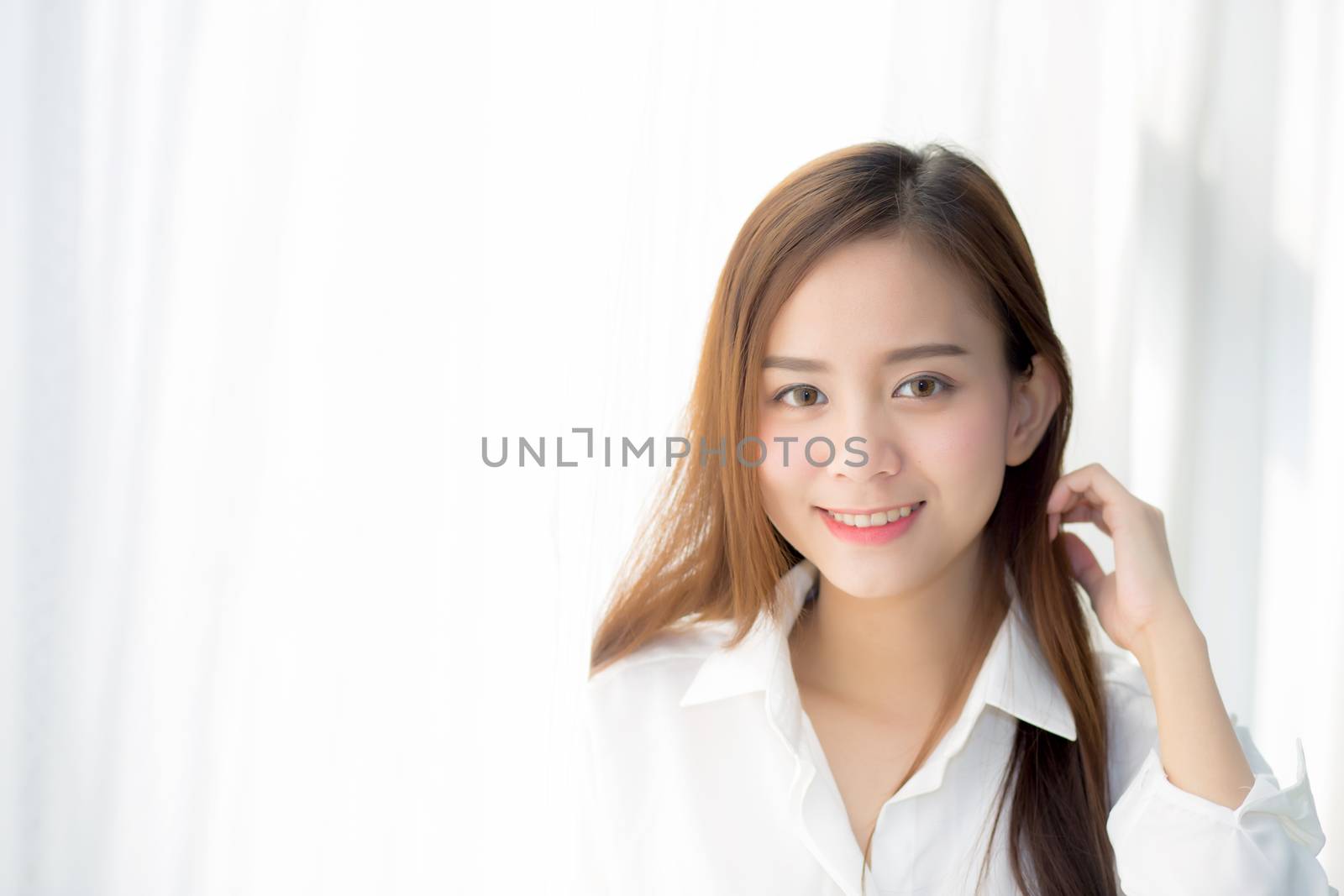 Portrait of beautiful young asian woman standing the window and smile while wake up with sunrise at morning, lifestyle and relax concept.
