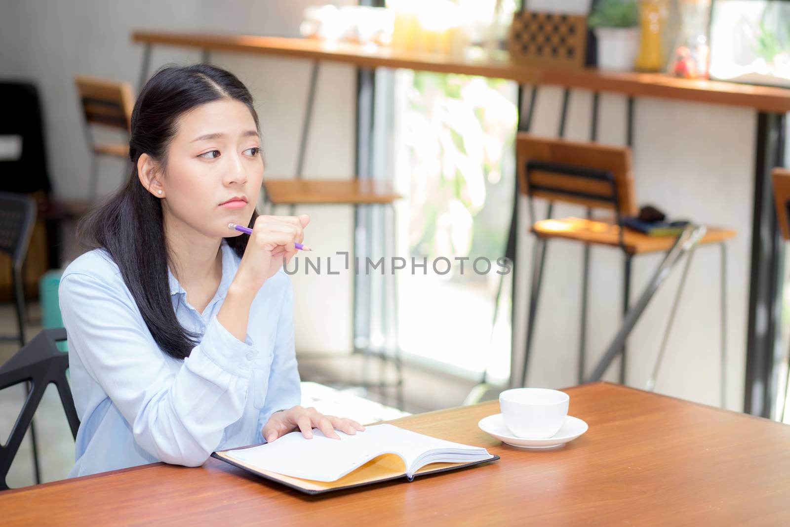 Beautiful of portrait business asian young woman thinking idea and writing on notebook on table, girl work at coffee shop, freelance business concept.