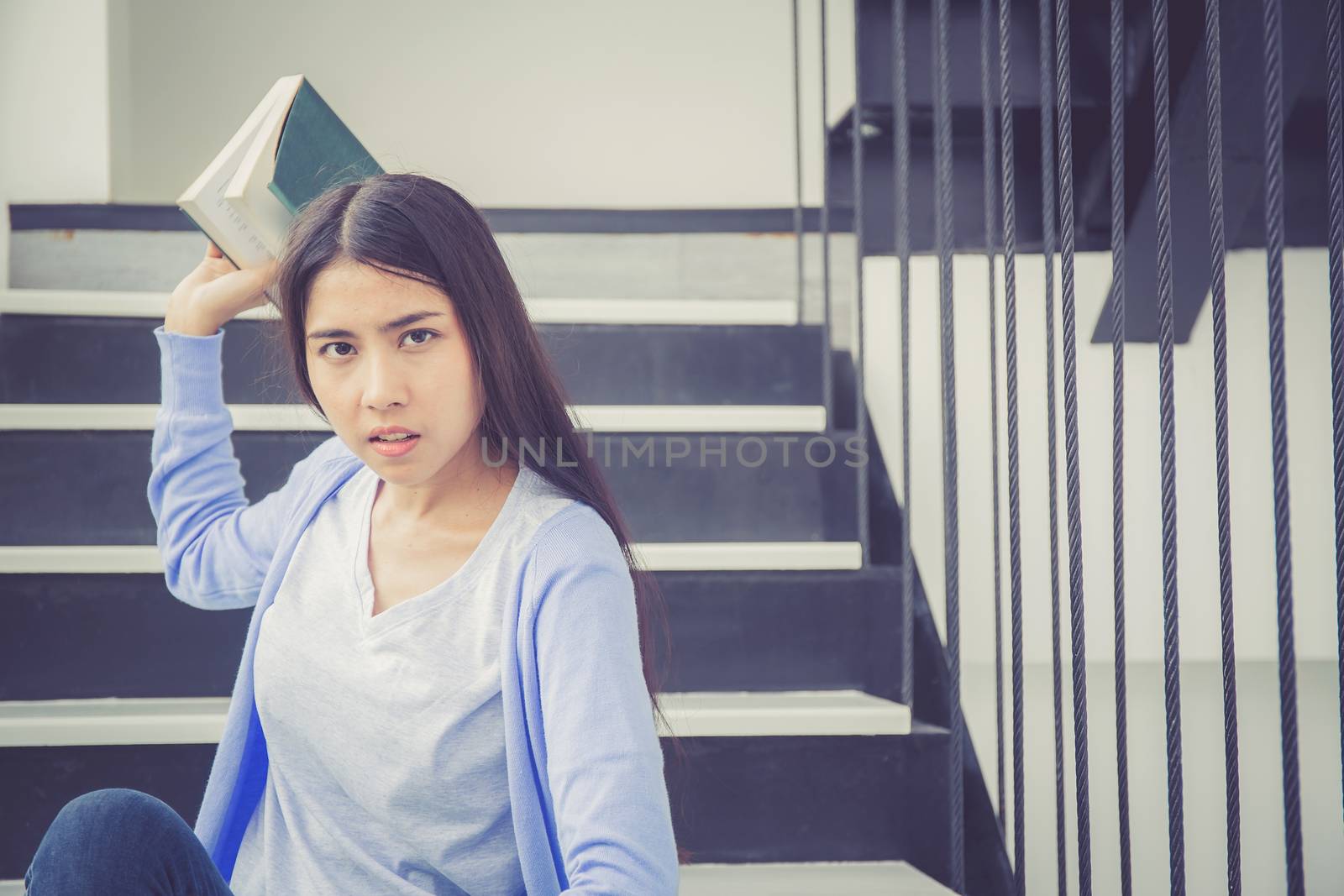 Beautiful of portrait asian young woman holding book, girl tired and bored reading book studying for exams, education and lifestyle concept.