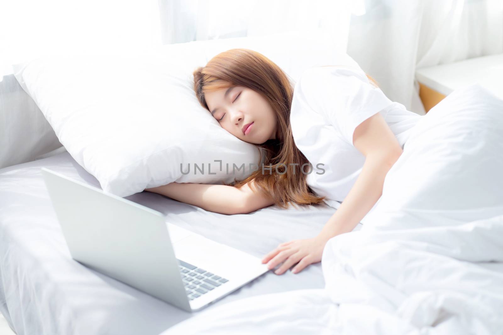 Beautiful of portrait young asian woman with laptop lying down in bedroom, girl tired sleep and relax with computer notebook, resting and healthcare concept.