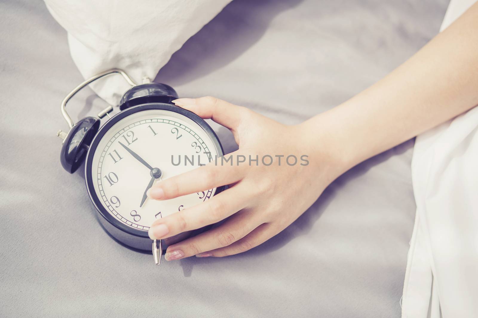 closeup asian young woman turn off alarm clock in good morning, wake up for sleep with  girl holding alarm clock, time and lifestyle concept.