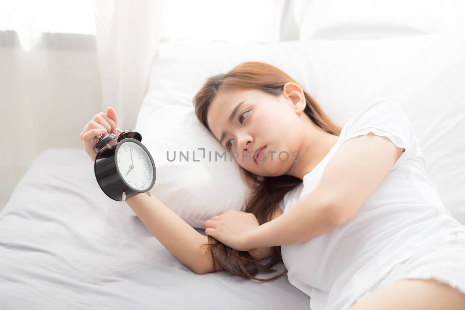 Beautiful asian young woman turn off alarm clock in good morning, wake up for sleep, girl holding alarm clock, time and lifestyle concept.