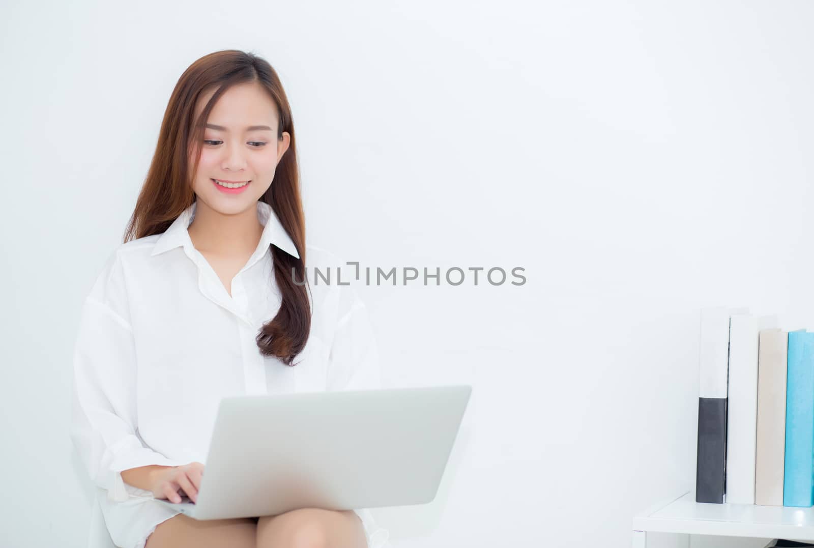 Beautiful young asian woman using laptop for leisure on sofa, gi by nnudoo