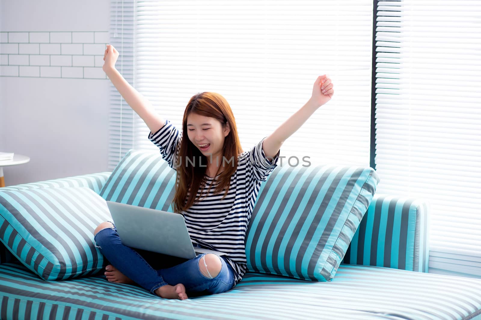 Beautiful happiness portrait of young asian woman using laptop w by nnudoo