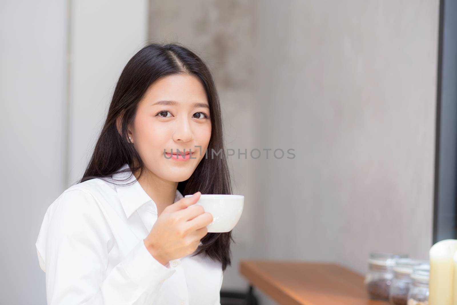 Beautiful  young asian woman drinking coffee and smile in the morning at cafe, girl sitting in coffee shop for breakfast and leisure during free time.