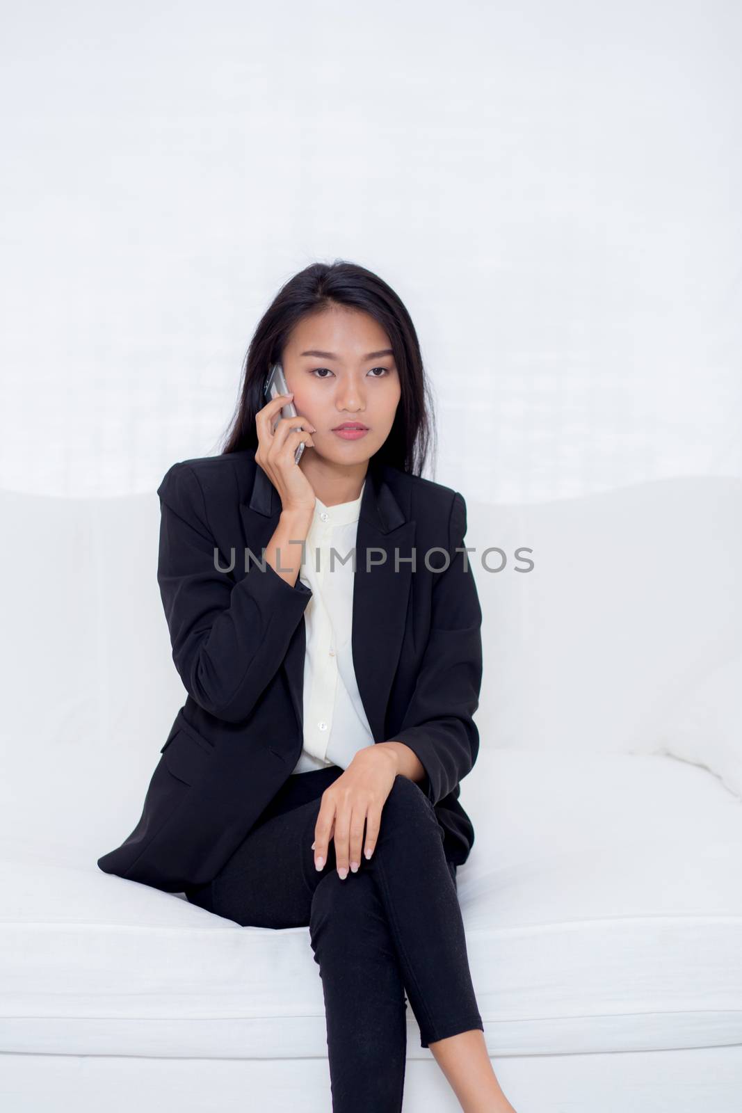 Beautiful young asian woman talking phone and smile in the living room, businesswoman sitting on sofa,businesswoman calling telephone, communication concept.