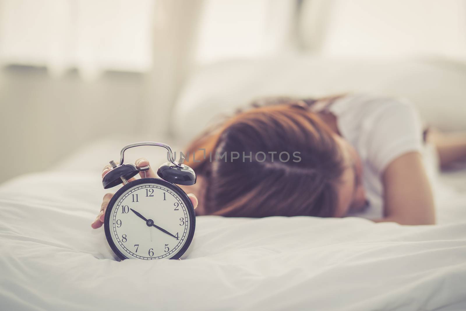 Beautiful asian young woman turn off alarm clock in good morning, wake up for sleep with closeup foreground alarm clock, relax and lifestyle concept.