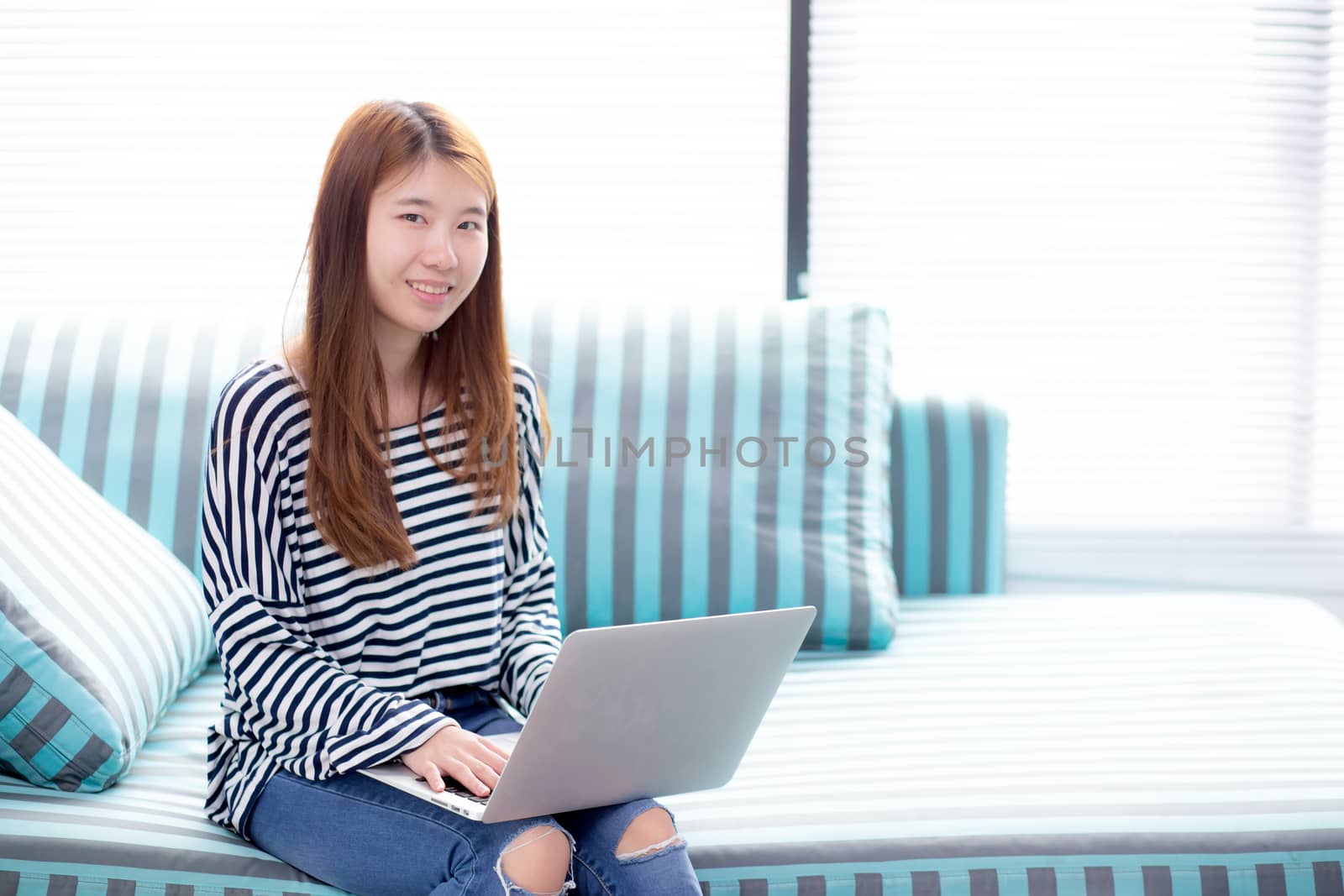 Beautiful of portrait young asian woman using laptop for leisure on sofa in living room, girl working online with notebook freelance with a happy, communication business concept.