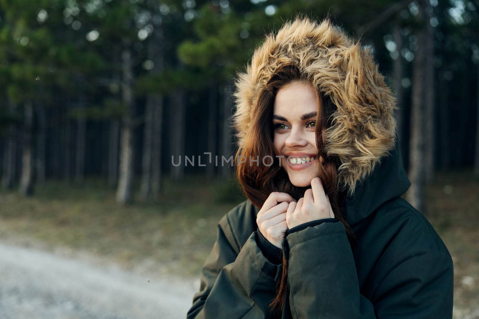 Woman jacket with a hood smile look aside the fresh air on the background of the forest. High quality photo