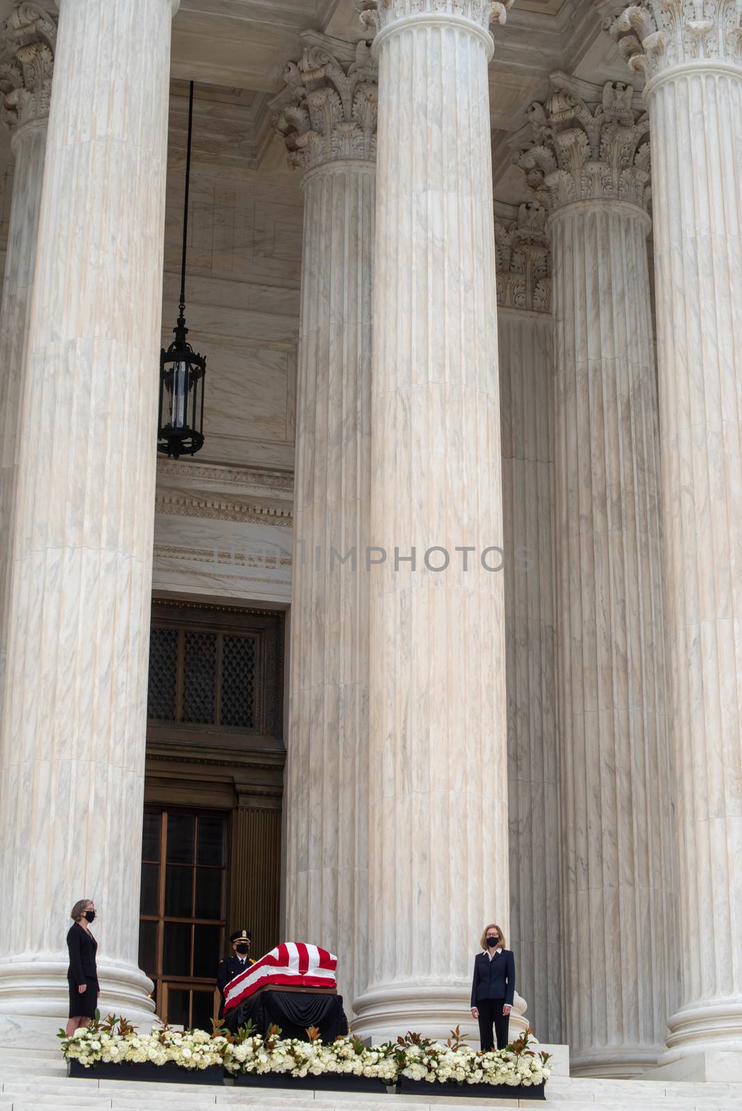 Washington, DC, USA / 9/24/2020: Justice Ruth Bader Ginsburg's casket draped in an American flag on the steps of the Supreme Court, pall bearers flowers, and tall columns in a vertical image editorial use.