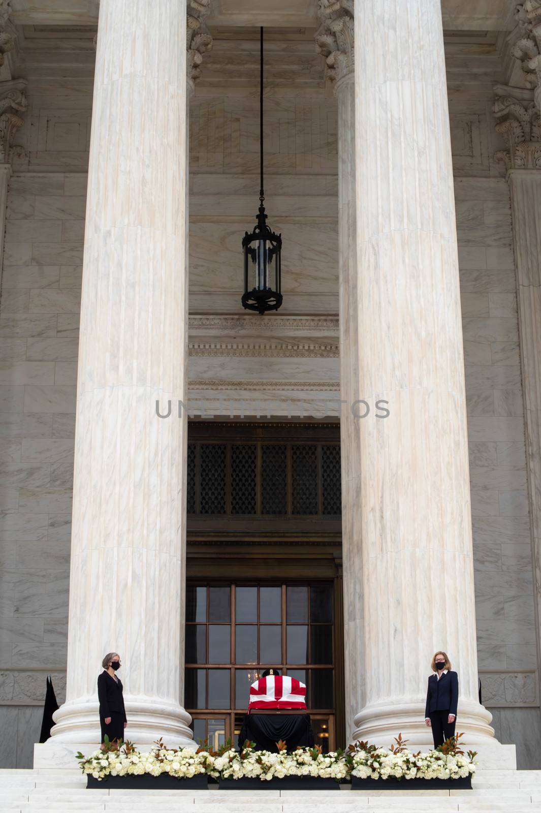 Washington, DC, USA / 9/24/2020: Justice Ruth Bader Ginsburg's casket draped in an American flag on the steps of the Supreme Court, pall bearers and tall columns in vertical image. Editorial use