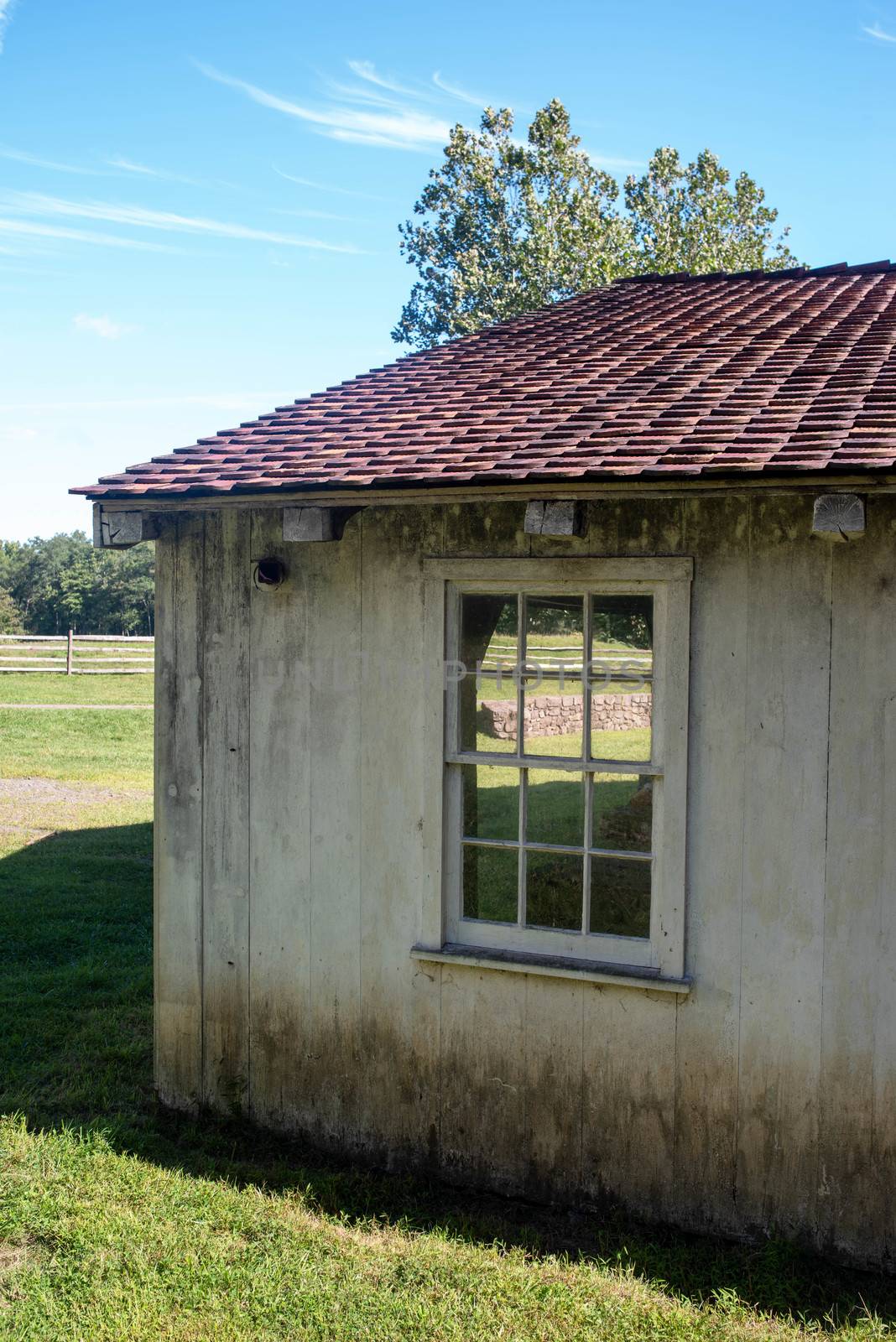 Whitewashed building at the idyllic colonial village, green pasture is seen through the window. Full frame with copy space.