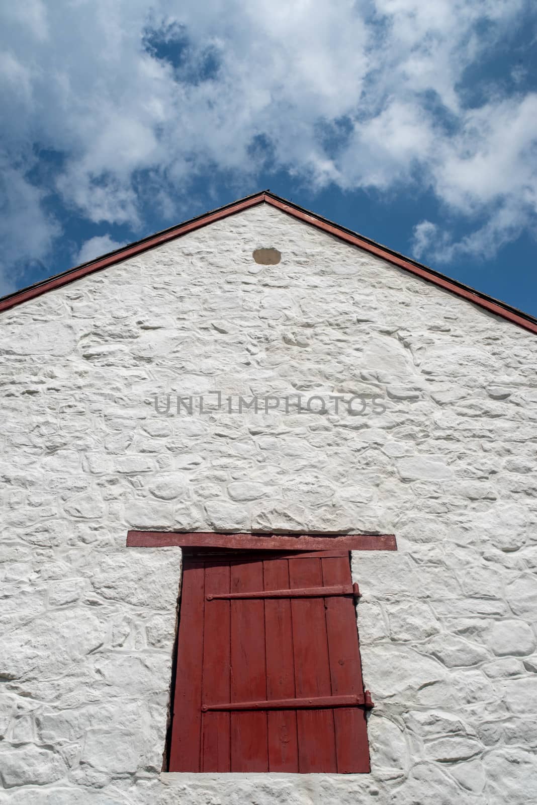 Red shutter, antique hinges, and pointed piqued roof on old farm by marysalen