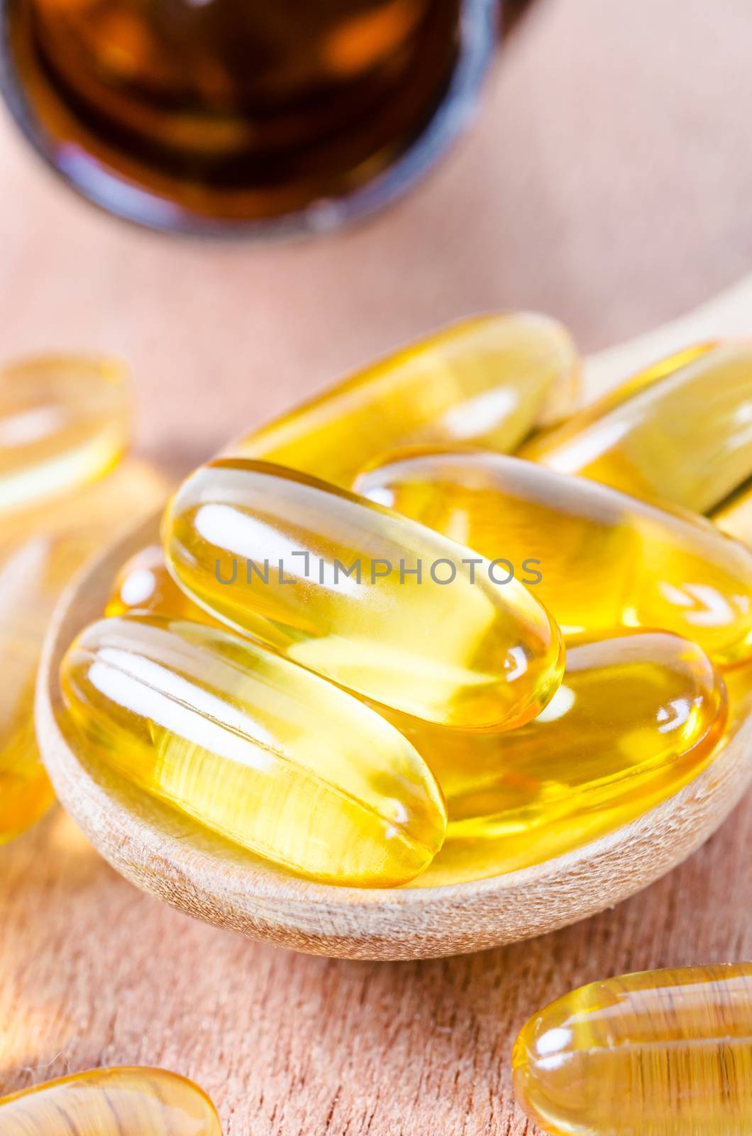 Fish oil capsules in wooden spoon with bottle on wooden background.