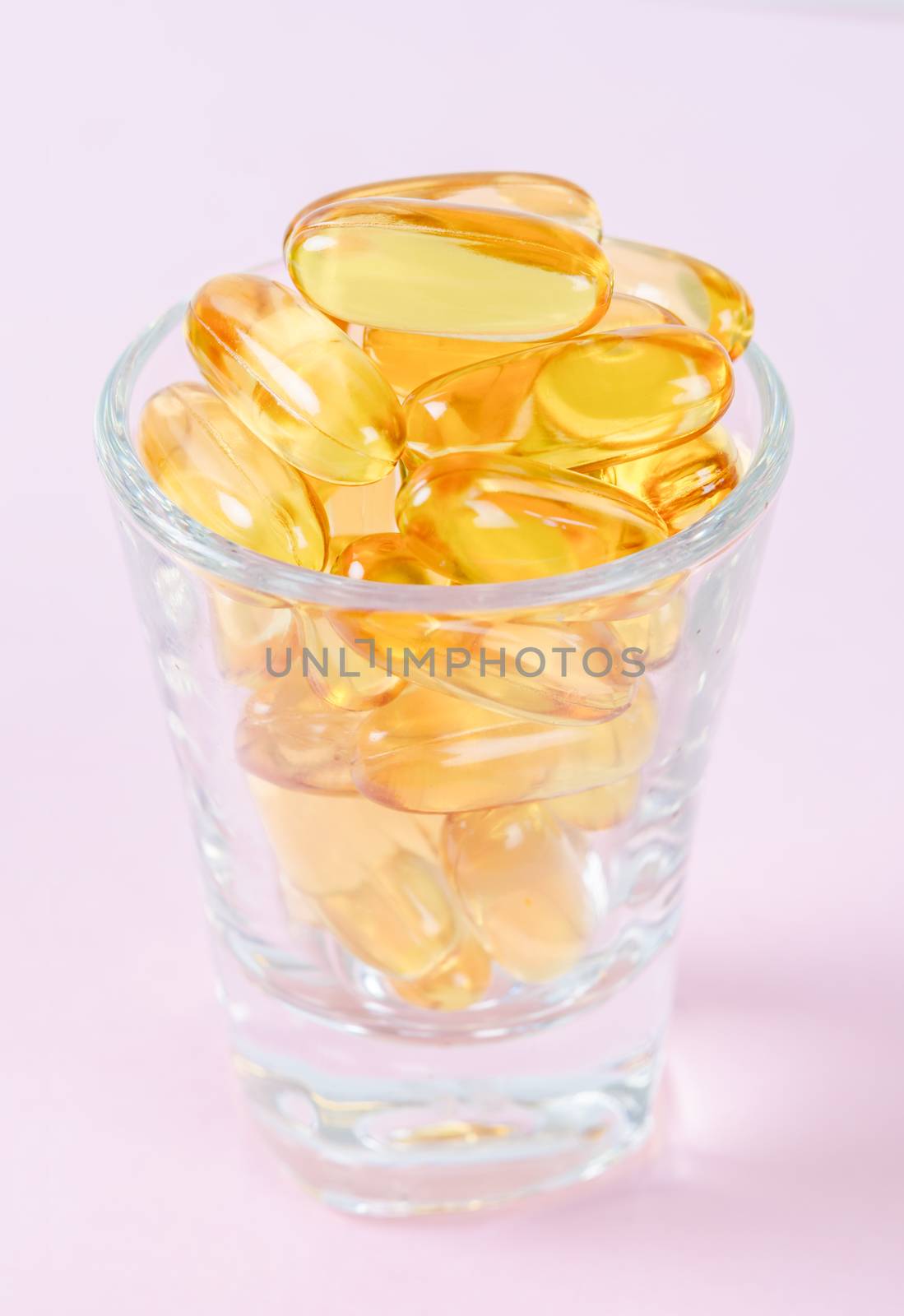 Fish oil capsules in glass. by Gamjai