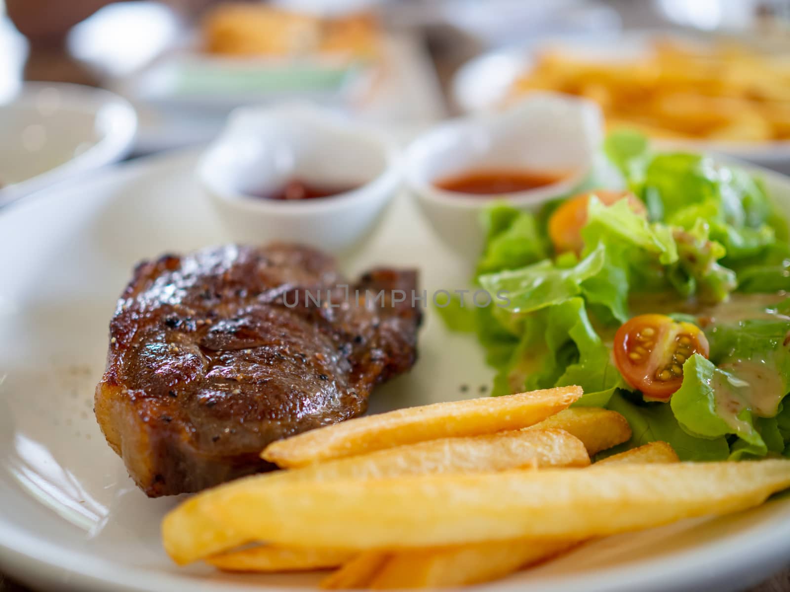 Close up pork steak on a white plate Has a blurred background. by Unimages2527